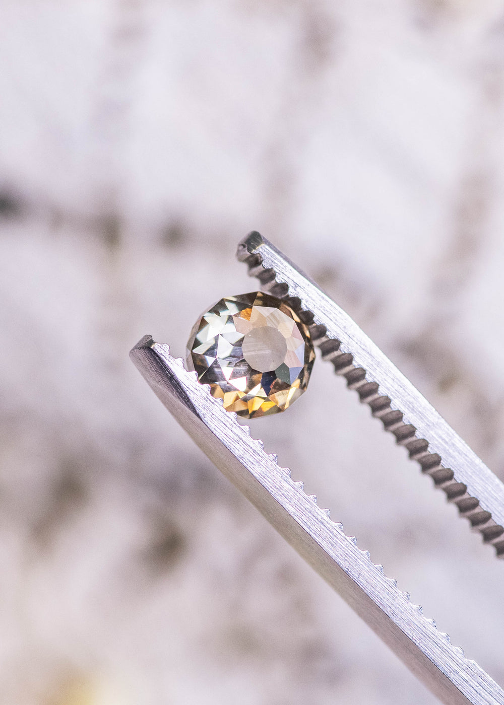 1.04 carat Mughal cut diamond with champagne fancy yellow brown color and blue fluorescence held in tweezers