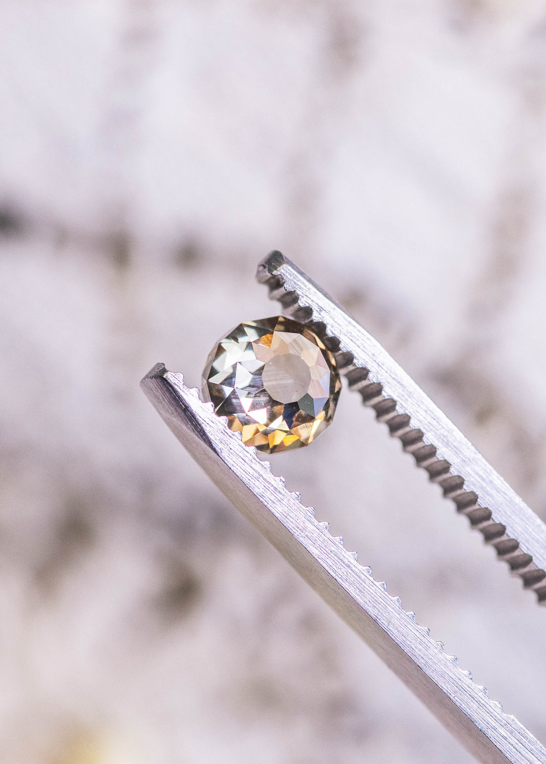 1.04 carat Mughal cut diamond with champagne fancy yellow brown color and blue fluorescence held in tweezers