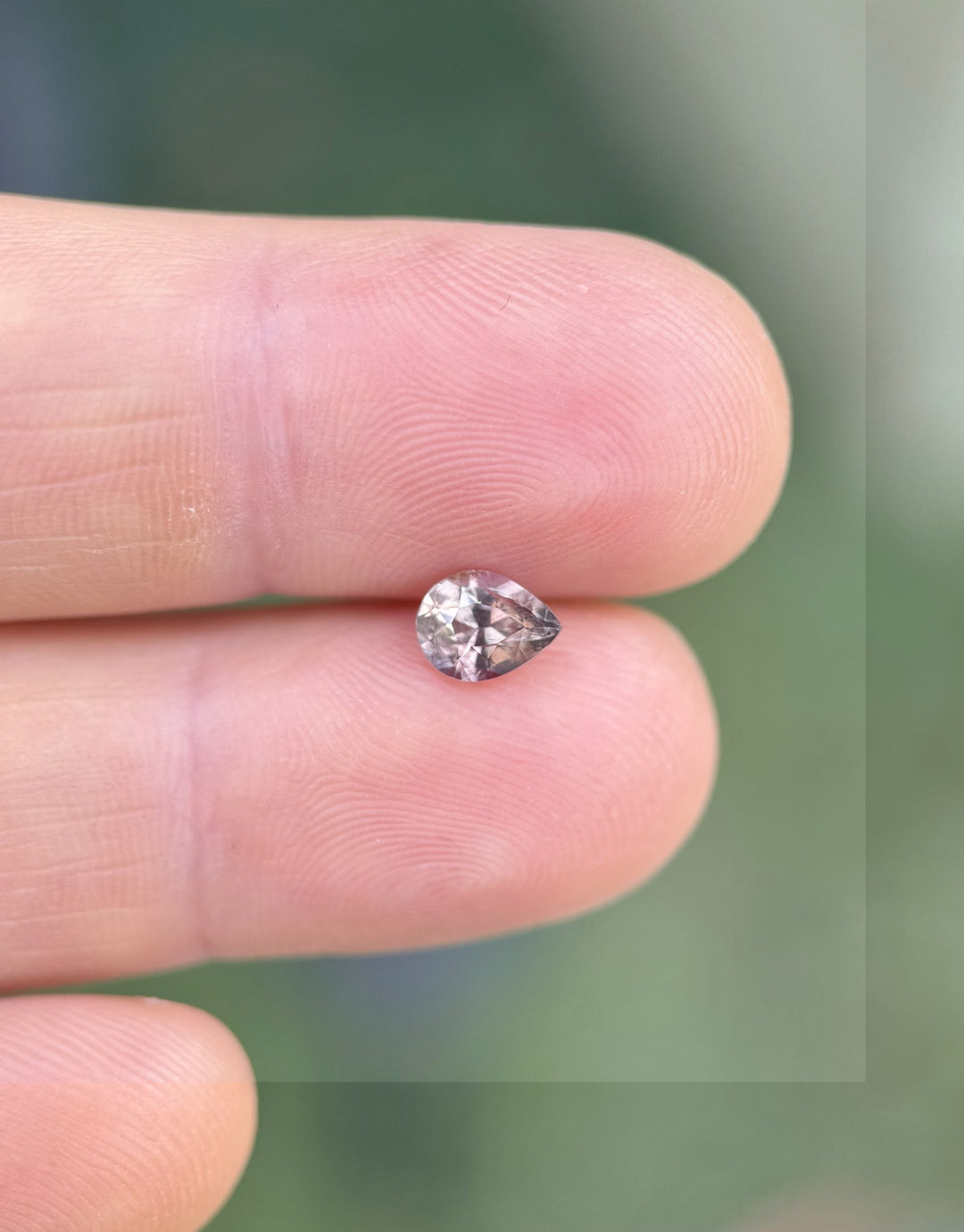 1.04ct pear cut sapphire showing soft earthy mauve tone on fingertip, Umba River Tanzania origin
