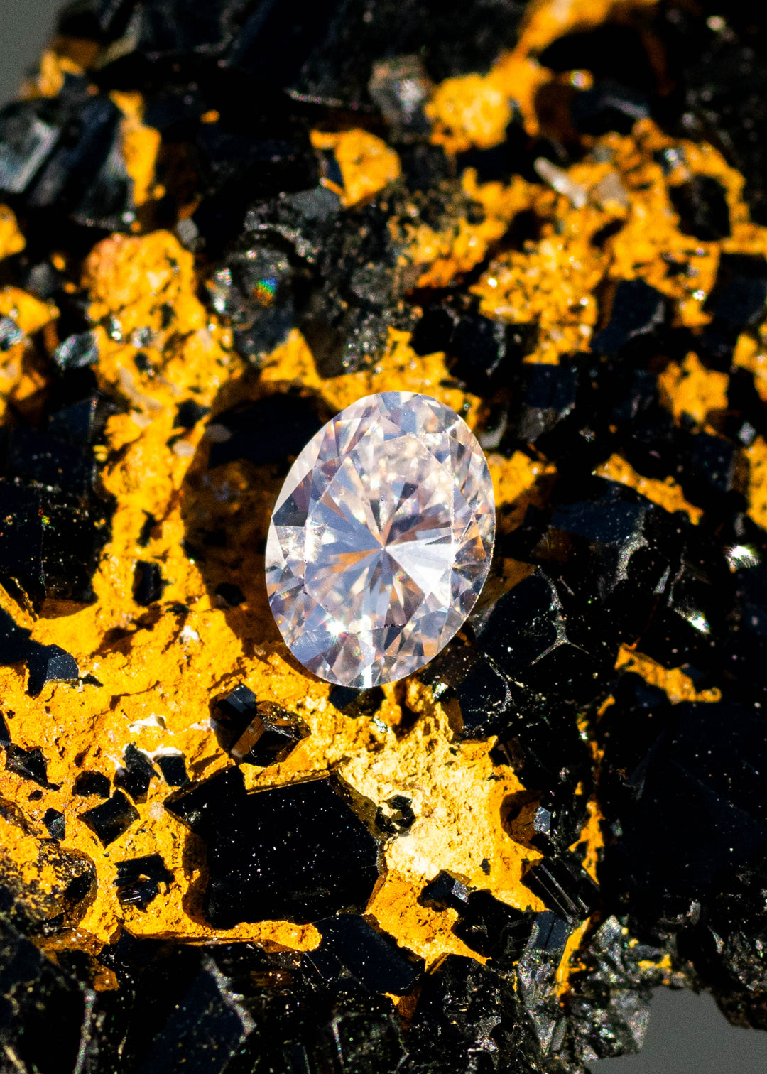 1.04ct champagne oval brilliant cut diamond from Canada resting on natural black tourmaline matrix under direct sunlight.