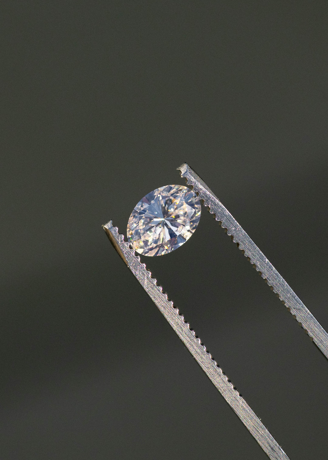 1.04ct champagne oval brilliant cut diamond from Canada held in gem tweezers under natural sunlight.