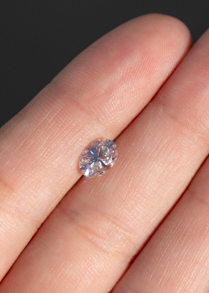 1.04ct champagne oval brilliant cut diamond from Canada held on fingertips under direct sunlight showing off scale.