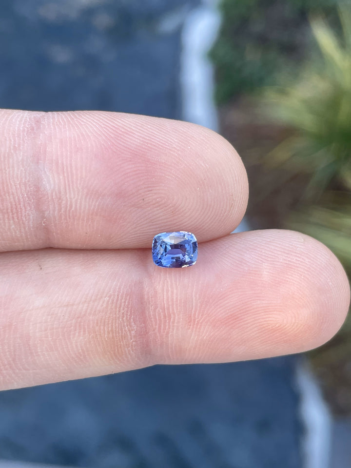 Close-up of a 1.05 carat radiant cut sapphire gemstone, opalescent with shades of purple to pink, sourced from Sri Lanka and untreated.
