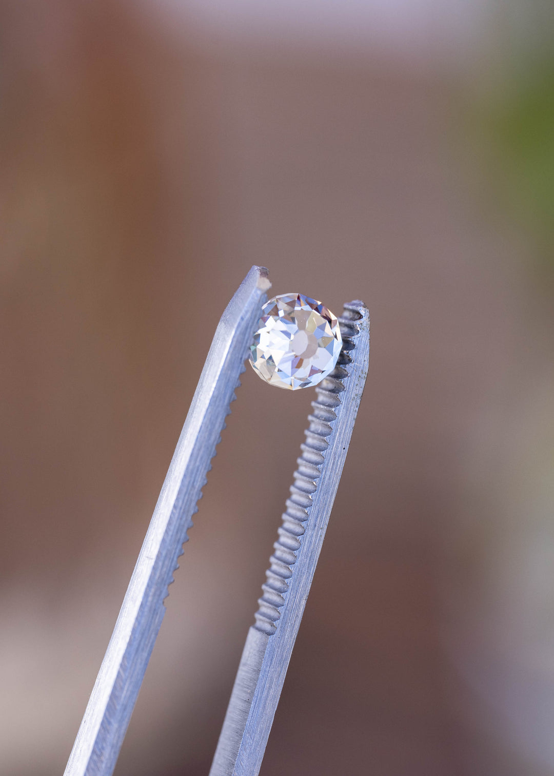 Close angled view of the 1.06 carat diamond among green leaves, showing its broad historic-inspired facets and changing pattern of light.