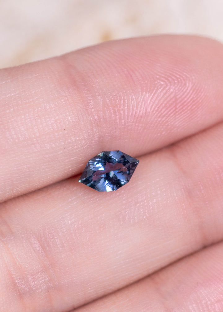 Loose 1.06 carat sapphire resting on fingertips, showing denim blue color and crisp modified brilliant marquise facets from Sakaraha, Madagascar.