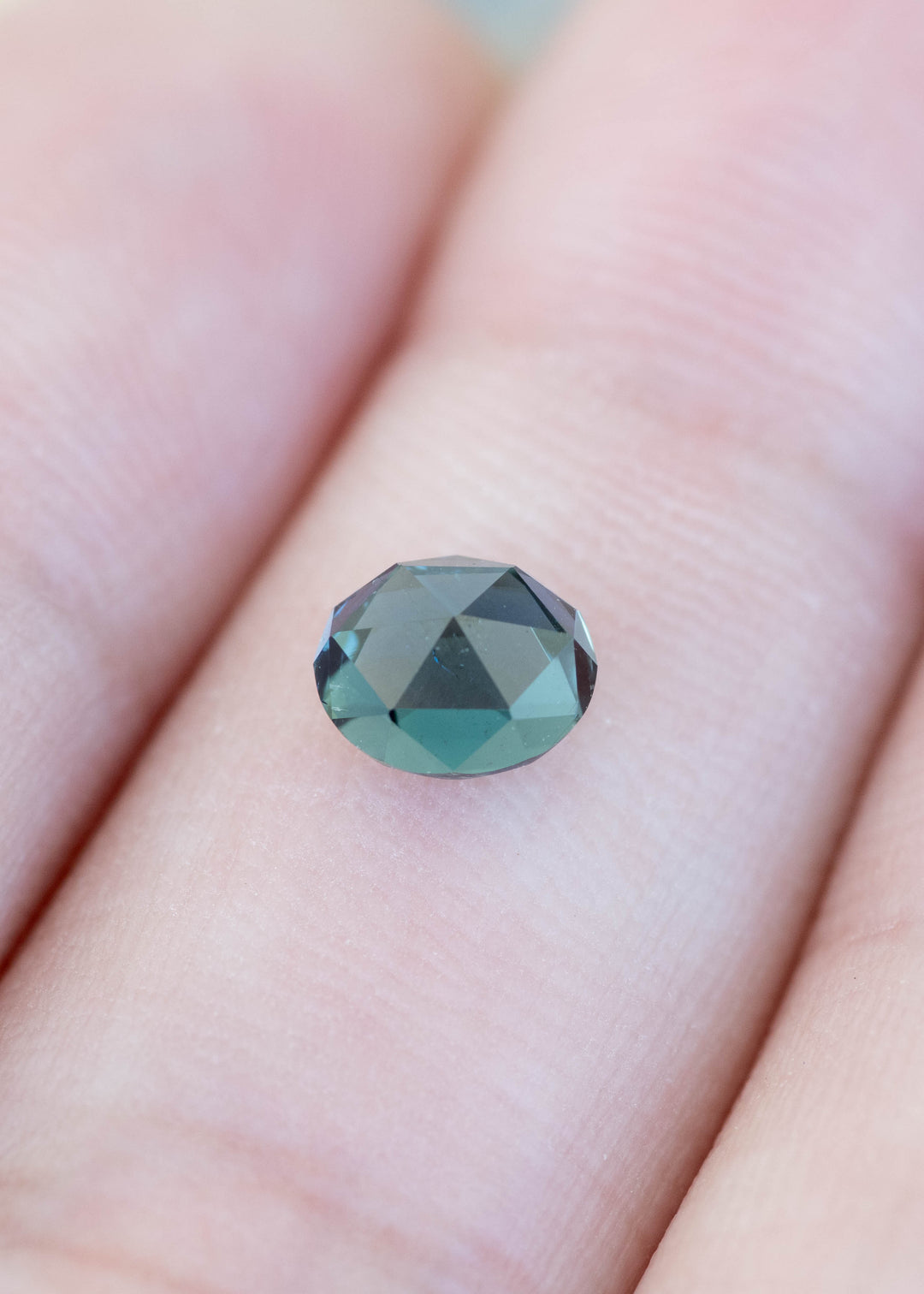 Oval teal sapphire double rose cut shown on finger for size reference