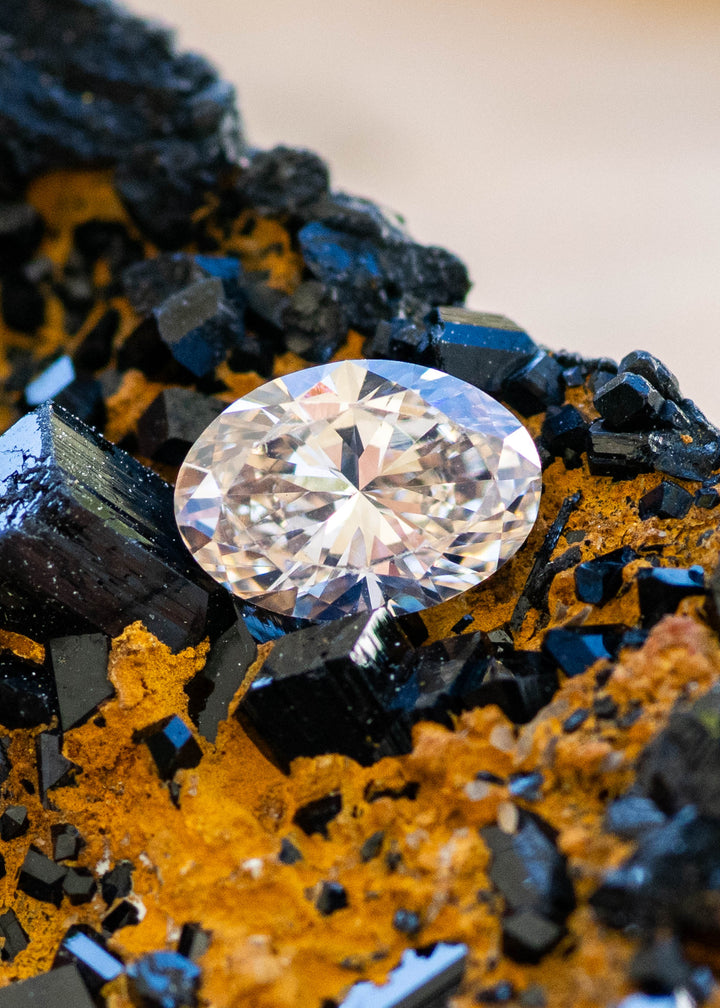 1.07ct natural champagne oval brilliant cut diamond from Canada resting on natural black tourmaline gemstone under natural light.