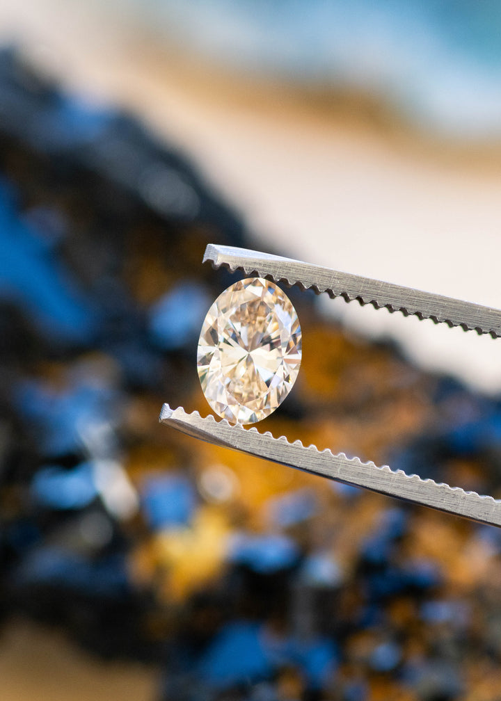 1.07ct natural champagne oval brilliant cut diamond from Canada held in gem tweezers showing off natural brilliance and color.