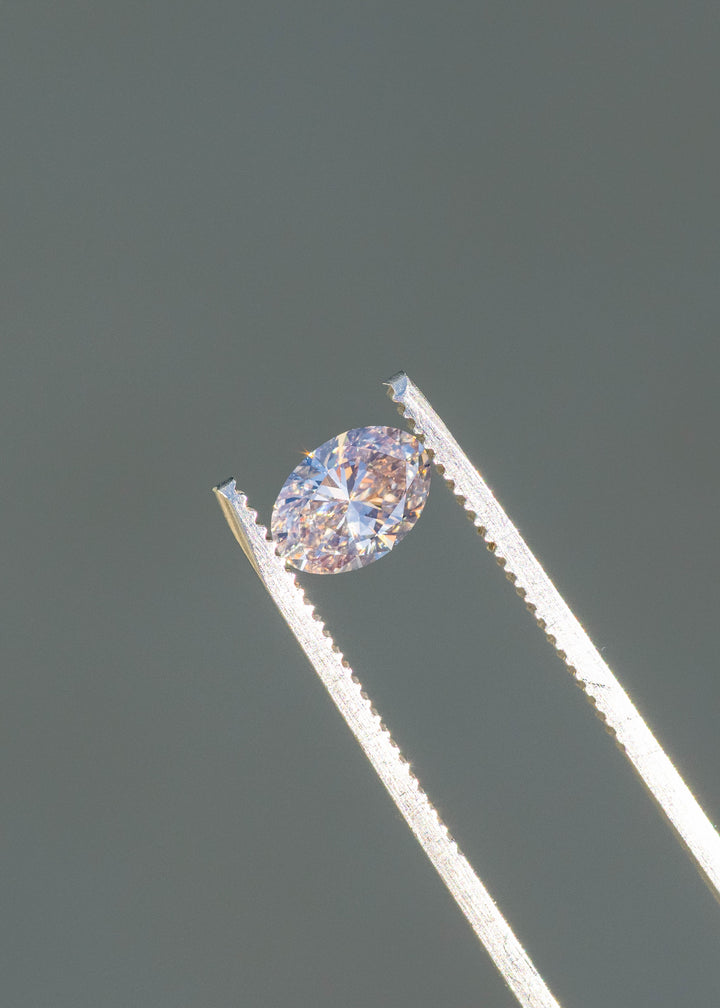 1.07ct natural champagne oval brilliant cut diamond from Canada held in gem tweezers under sunlight showing natural color and brilliant sparkle.