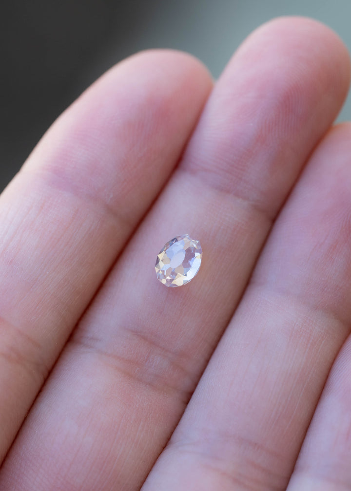 1.08 carat South African diamond resting on a fingertip for scale, showing its softly irregular oval outline and elongated central table.