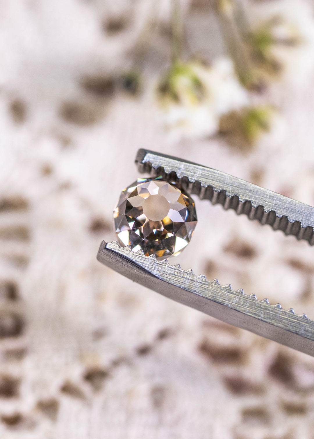 Loose fancy brown Mughal cut diamond held in tweezers, highlighting the historic faceting style and natural champagne color from South Africa.