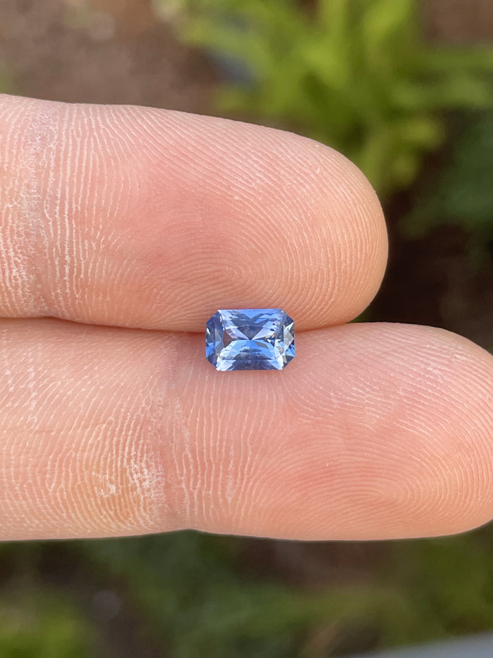 Close-up of a 1.10 carat sapphire gemstone with radiant cut, featuring blue and lavender hues, untreated and sourced from Sri Lanka.