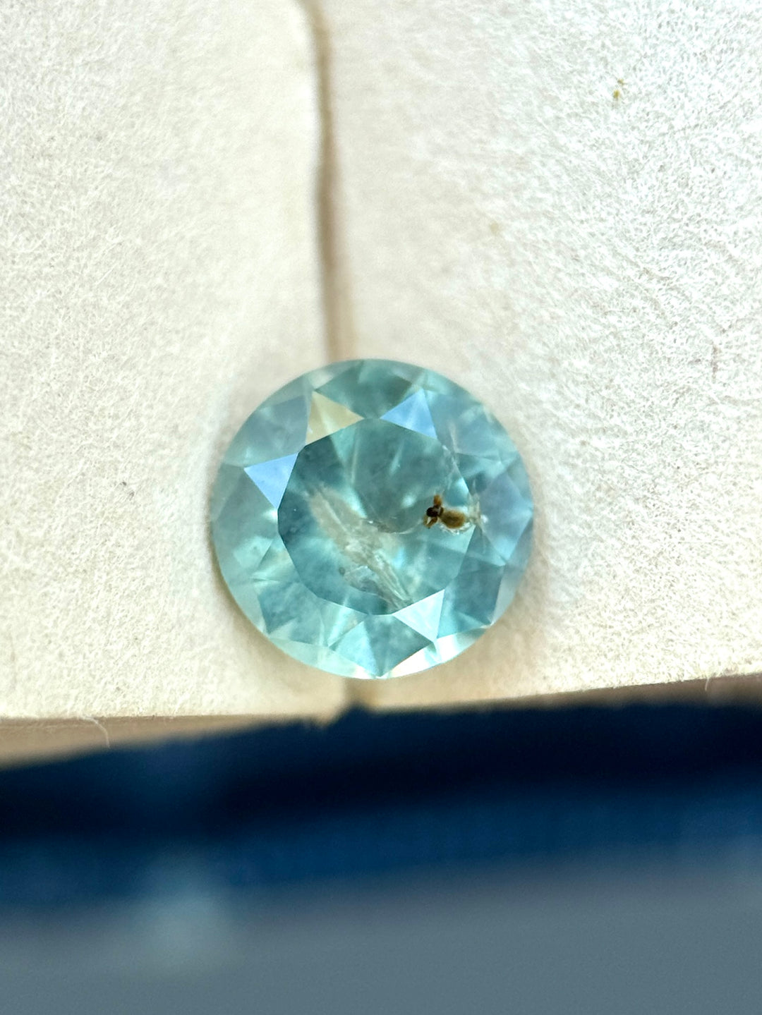 1.10 carat opalescent powder teal sapphire shown face-up, displaying a round cut and soft seafoam-blue color from Montana.