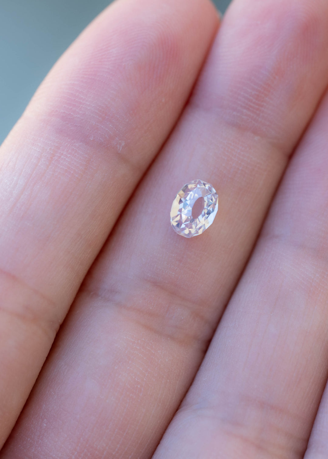 Oval Mughal cut South African diamond resting on a fingertip for scale, showing its 6.51 × 4.88 mm face-up proportions and antique-inspired facet pattern.