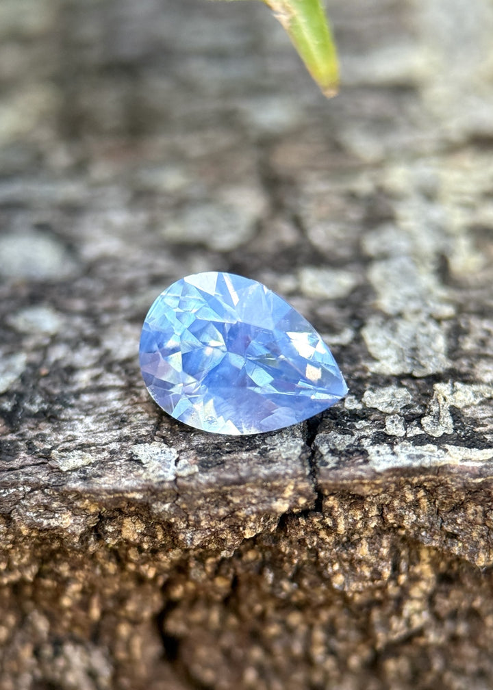 Loose 1.11 carat opalescent cornflower blue sapphire from Nigeria shown face-up, displaying the precision brilliant pear cut and soft glowing color.
