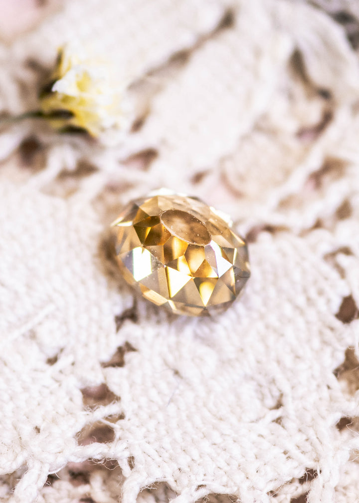 Loose 1.12 carat champagne fancy yellow brown Mughal cut diamond from South Africa shown face-up on lace, highlighting its warm golden-brown tone and domed faceting.