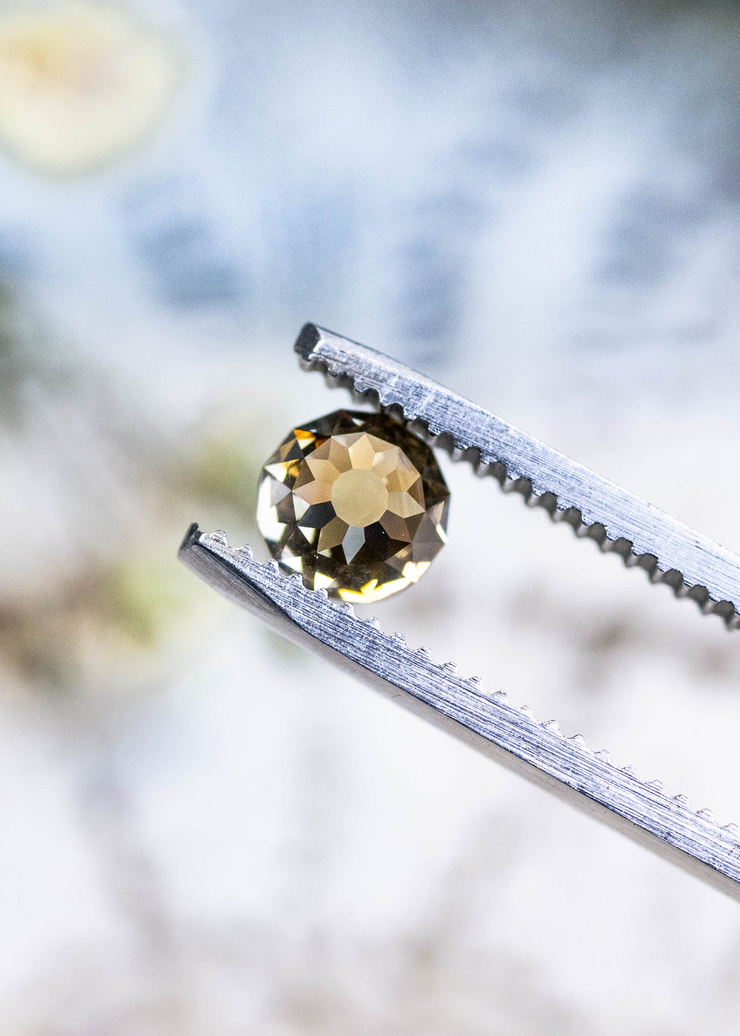 Loose 1.14 carat fancy yellow brown diamond held in tweezers, showing the Mughal cut pattern and champagne body color from South Africa.