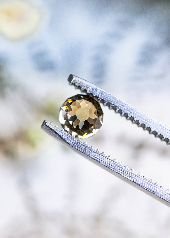 Loose 1.14 carat fancy yellow brown diamond held in tweezers, showing the Mughal cut pattern and champagne body color from South Africa.