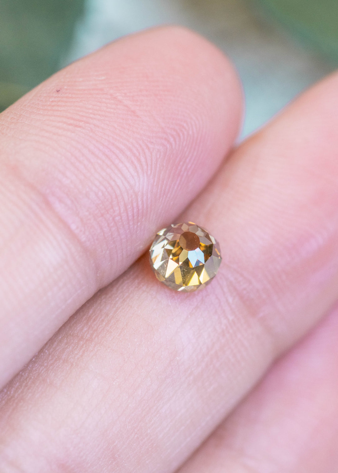Loose 1.14 carat fancy yellow brown Mughal cut diamond resting on fingertips, showing its antique style cut and natural brilliance.