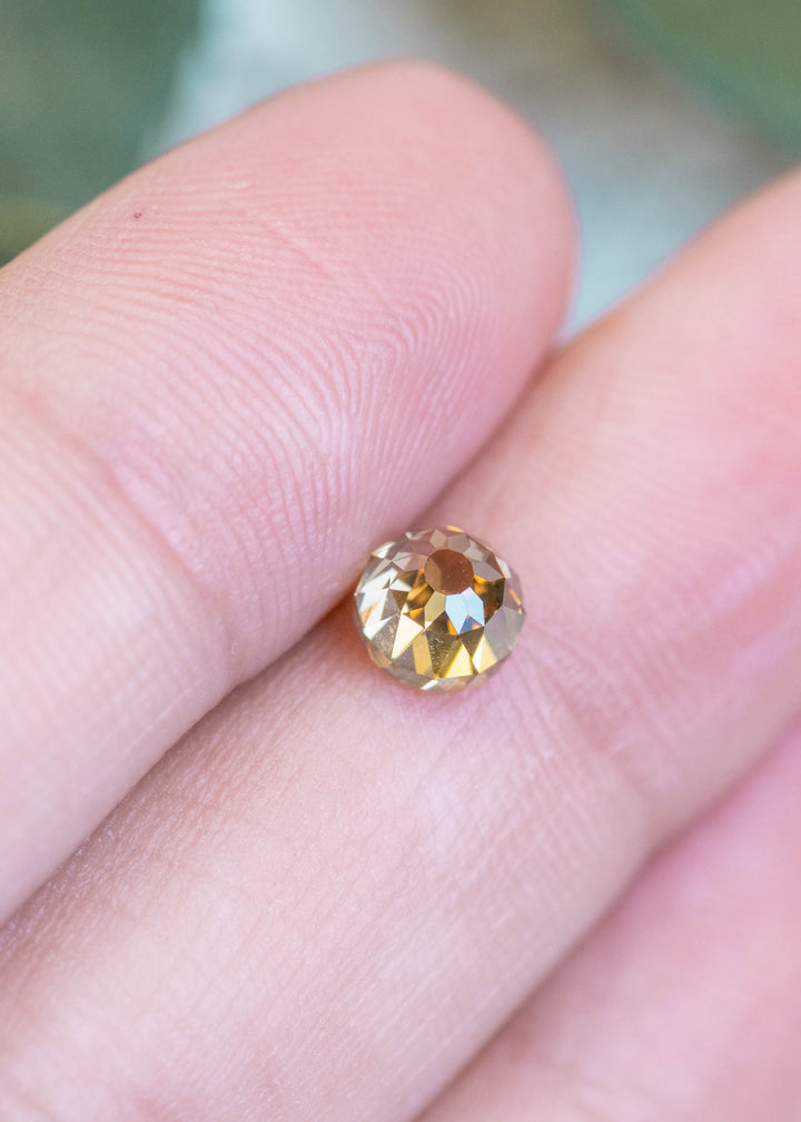 Loose 1.14 carat fancy yellow brown Mughal cut diamond resting on fingertips, showing its antique style cut and natural brilliance.
