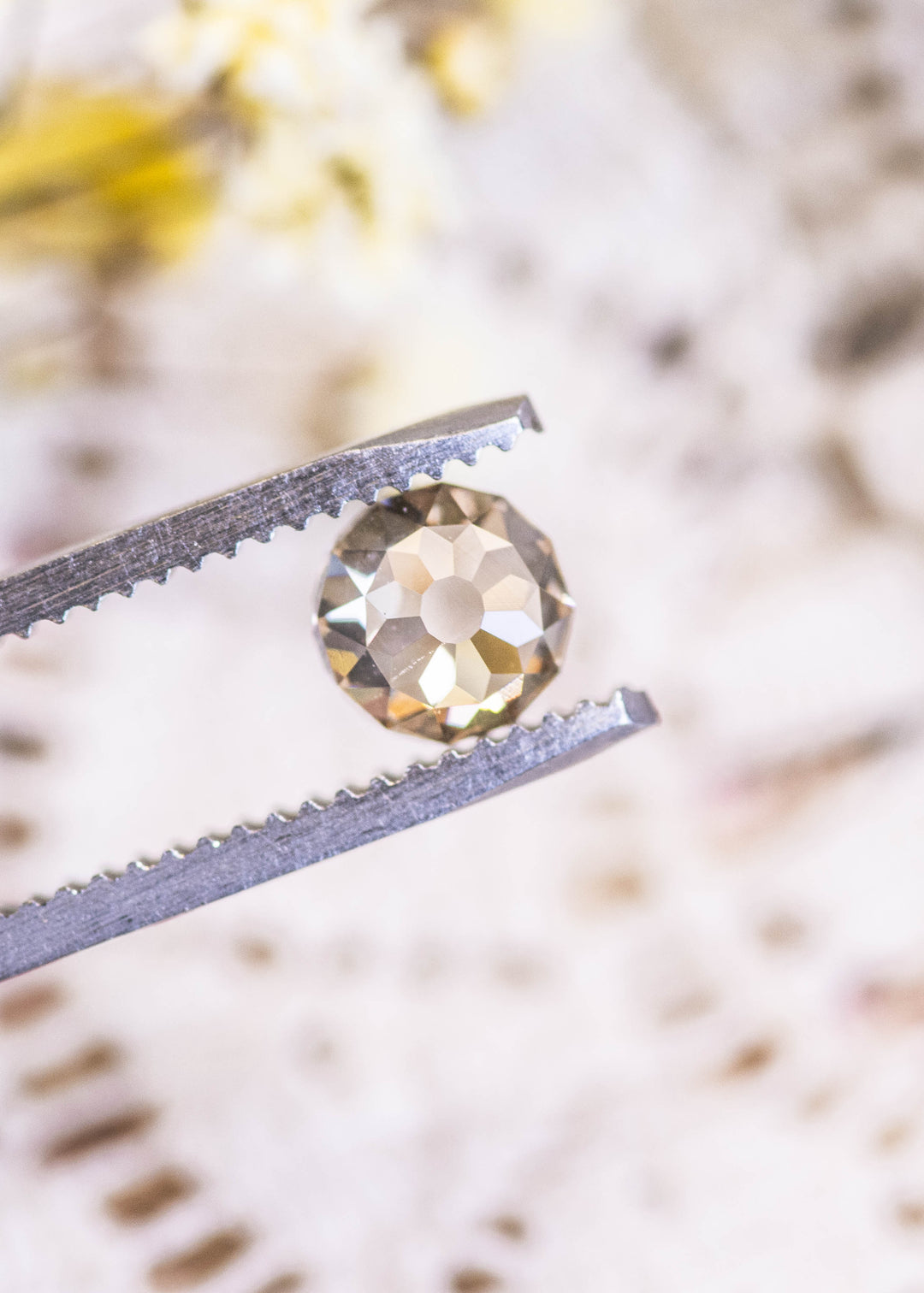 Loose champagne fancy light brown Mughal cut diamond from South Africa held in tweezers, showing the domed faceting and VVS1 clarity.