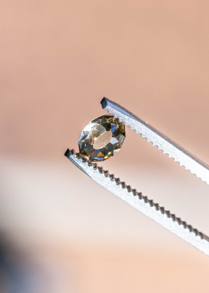 Loose fancy brown champagne Mughal cut diamond held in tweezers, showcasing its domed crown and detailed geometric facet pattern.