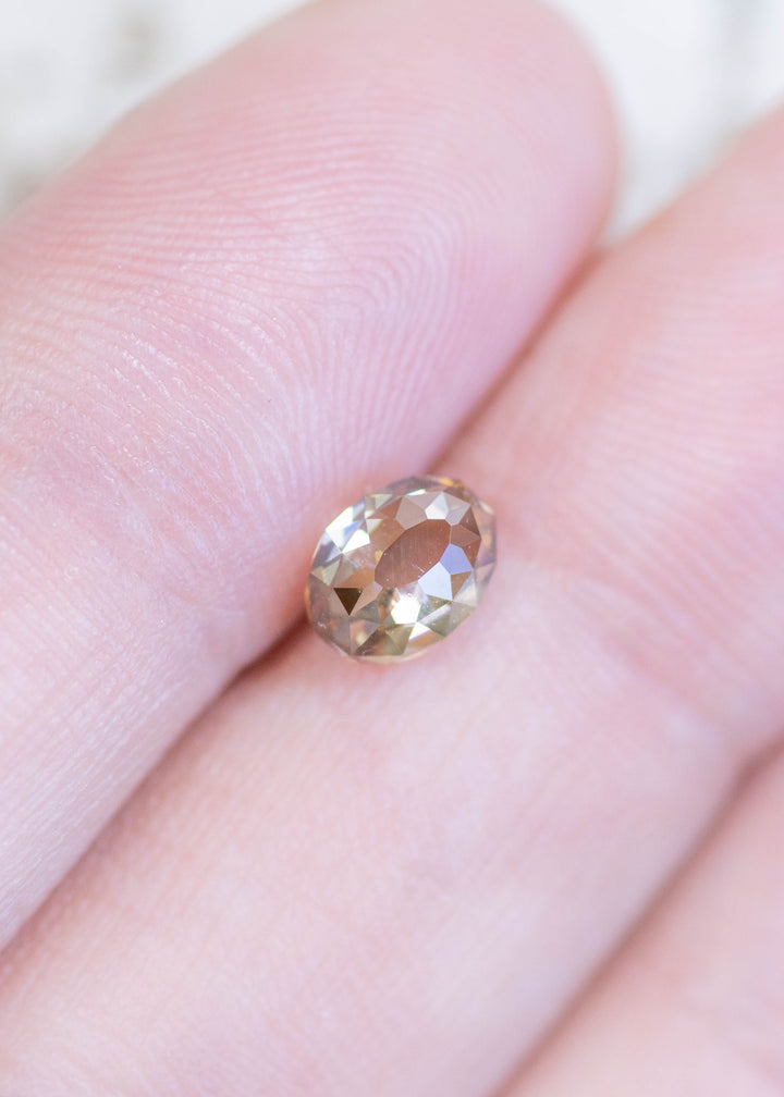 Loose fancy brown champagne Mughal cut diamond resting on fingertips, showing its scale, clarity, and warm champagne coloration.