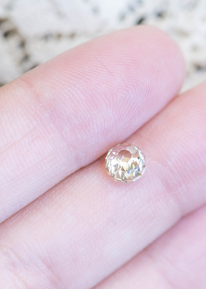 Loose fancy light brown champagne diamond in Mughal cut resting on fingertips, showing its size, warm color, and unique faceting pattern.