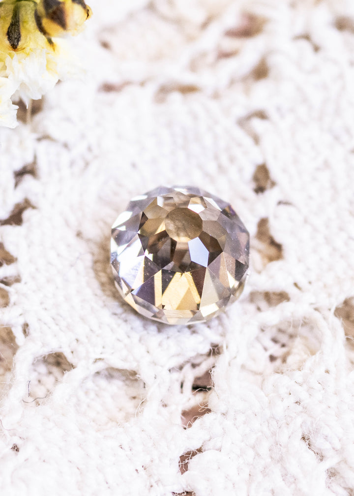 Loose fancy yellow brown Mughal cut diamond displayed face-up on lace, showing its warm champagne tones and intricate faceting.