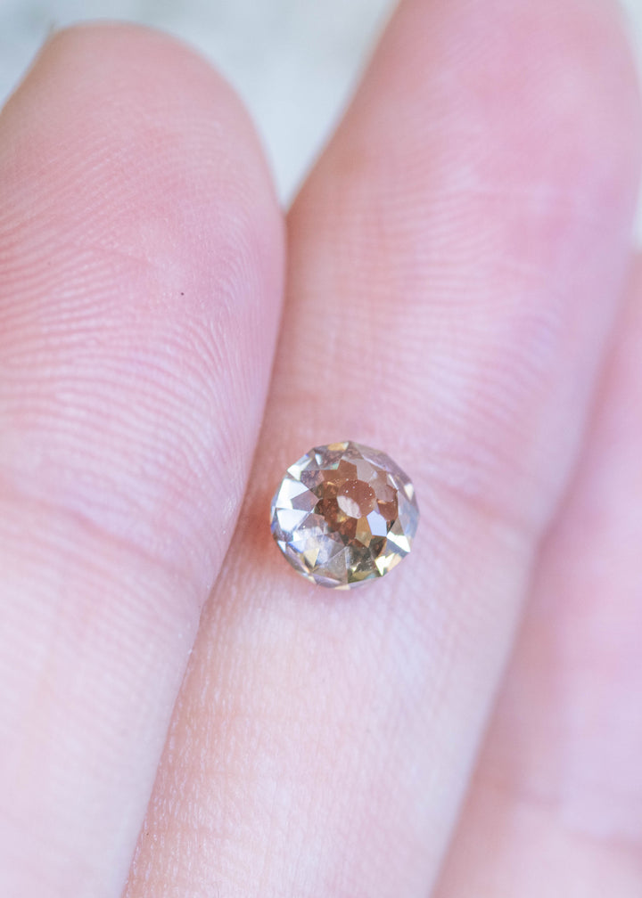 Loose fancy yellow brown Mughal cut diamond resting on fingertips, illustrating its size, clarity, and warm champagne color.