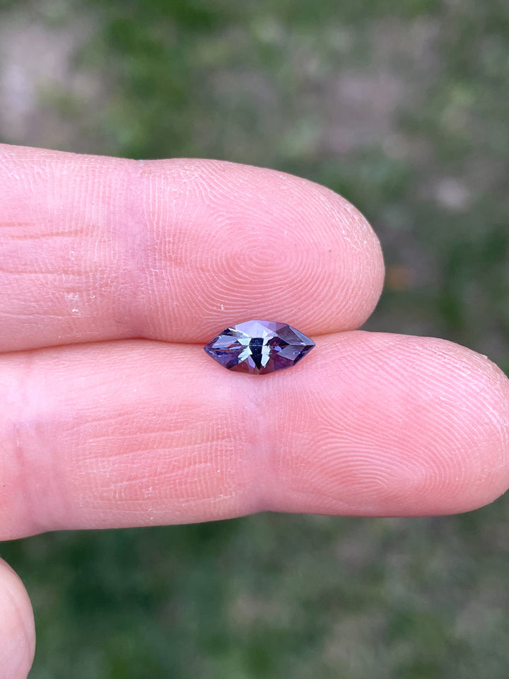 1.17 carat Tanzanite shown on fingertip in natural light, displaying geometric marquise faceting and rich purple-violet tones.