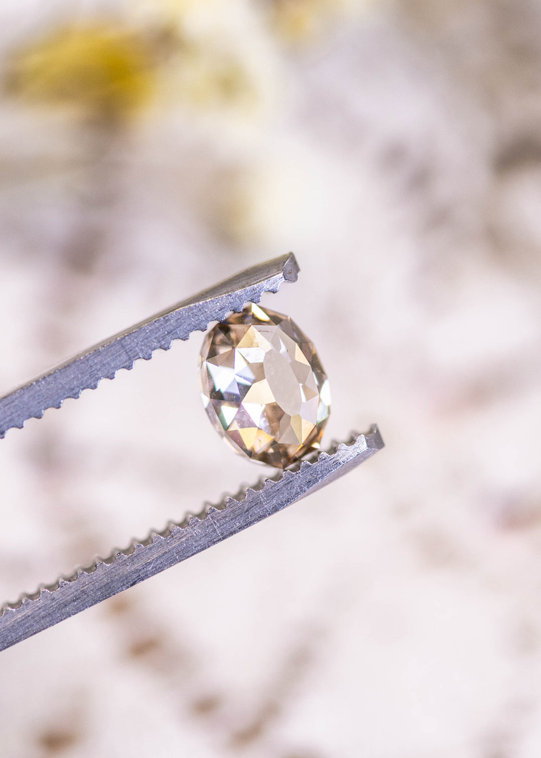 Loose 1.18 carat fancy light brown Mughal cut diamond from South Africa held in tweezers, highlighting the rounded Mughal faceting and champagne body color.