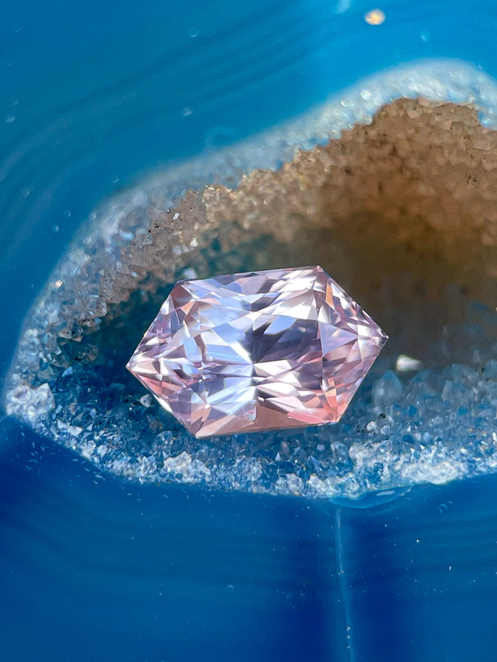 Close-up of a 1.20 carat sapphire gemstone with hexagonal mixed cut, featuring peach and pink hues, untreated and sourced from Sri Lanka.
