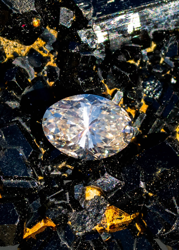 1.23ct champagne oval brilliant cut diamond from Canada resting on natural tourmaline gemstone under direct sunlight.