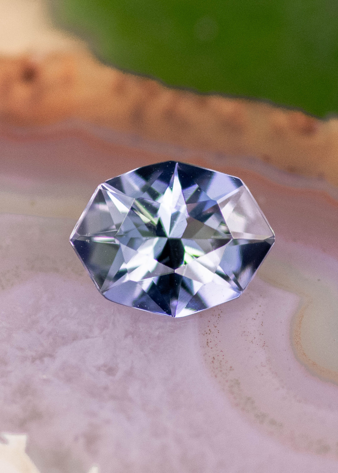 1.27 carat teal blue purple Tanzanite displayed on natural stone surface, custom geometric marquise cut with crisp angular edges and bright internal brilliance for custom fine jewelry