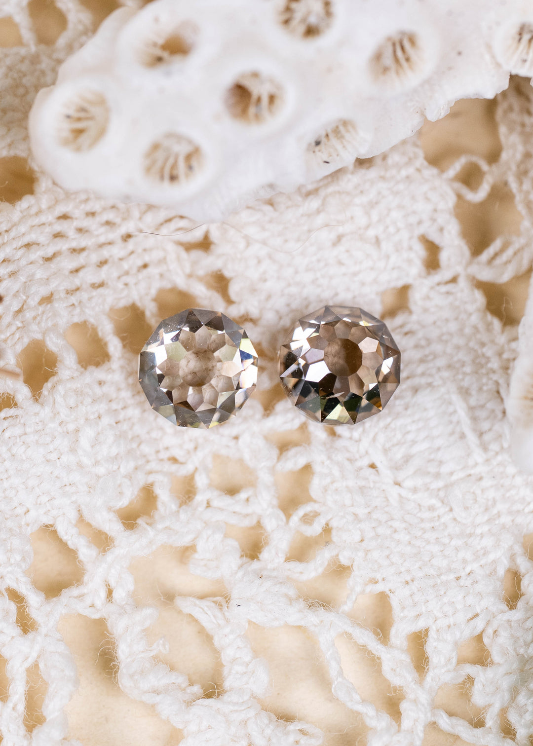 A pair of South African Round Mughal cut diamonds weighing 1.32 carats total, photographed on ivory lace. Their contrasting C1–C3 champagne tones, VVS2 clarity, and distinctive geometric faceting create an elegant antique-inspired appearance.
