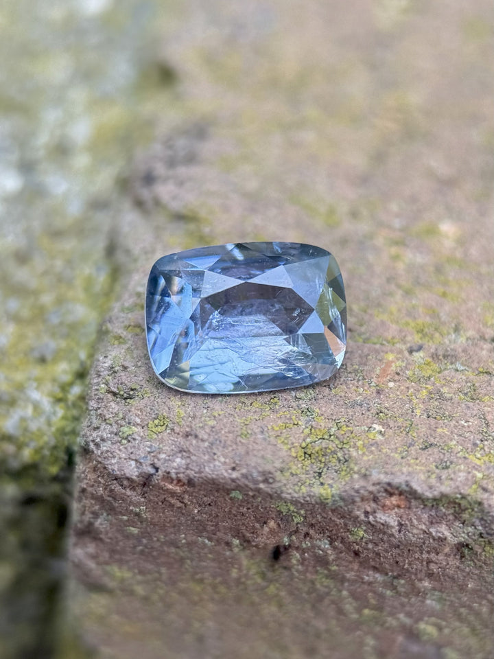 1.33 carat unheated periwinkle blue sapphire from Sri Lanka, custom elongated cushion cut displayed on a natural stone background
