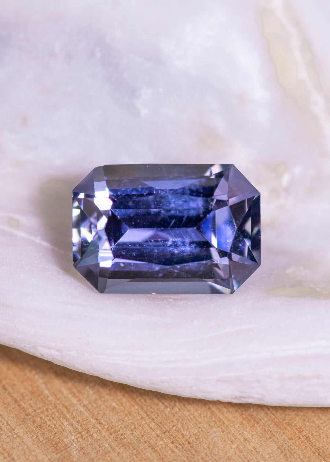 Loose mermaid purple, blue, and green tanzanite from Merelani Hills shown face-up on a white surface, displaying the custom modified radiant cut and natural color shift.