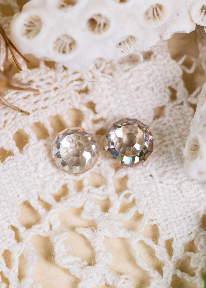 A pair of Round Mughal cut diamonds from South Africa, weighing 1.39 carats total. Photographed on ivory crocheted lace, their pale C1–C2 champagne coloration, VVS1 clarity, and distinctive geometric faceting create a refined antique-inspired appearance.