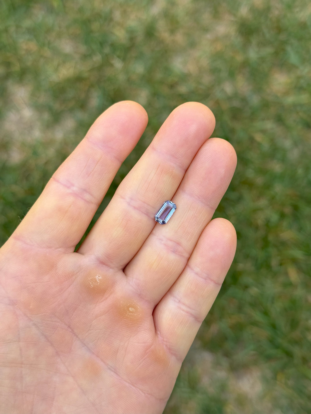 1.41ct modified emerald cut violet-blue sapphire from Umba River Tanzania shown on hand for scale