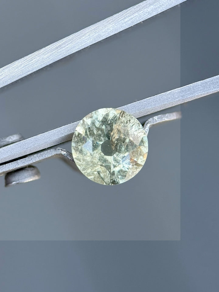 1.42ct Umba River sapphire in old European mine cut held in tweezers – showcasing natural teal, yellow, and green tones with antique sparkle.