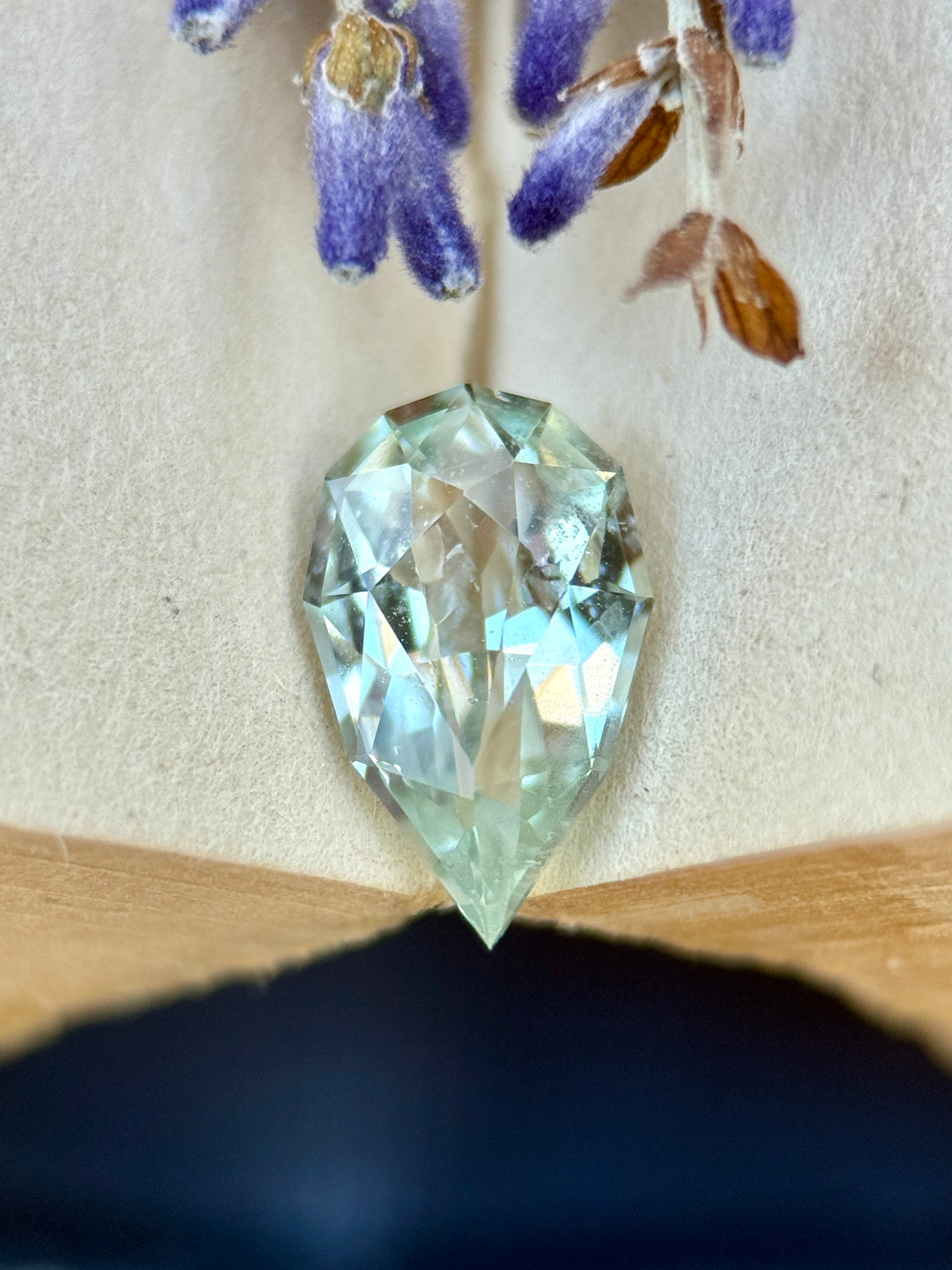 1.43 carat light seafoam green sapphire shown face-up, displaying precision pear cut faceting and soft pastel color from Madagascar.