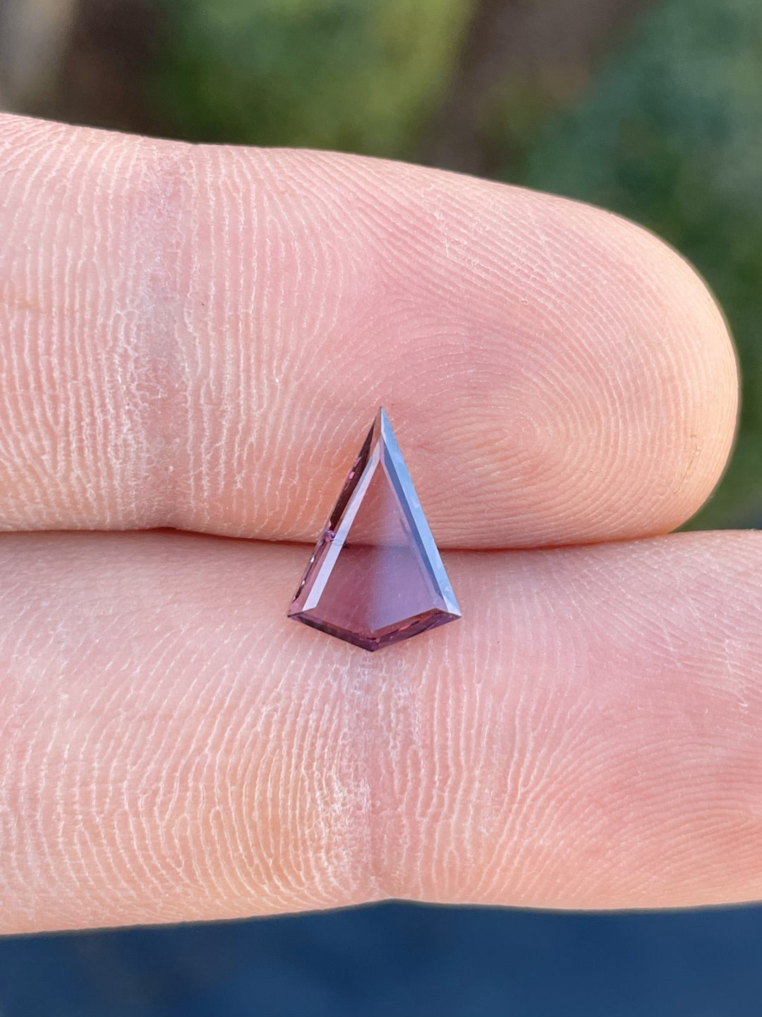 Close-up of a 1.44 carat purple-pink spinel gemstone, featuring a custom kite portrait step cut, untreated and sourced from Sri Lanka.