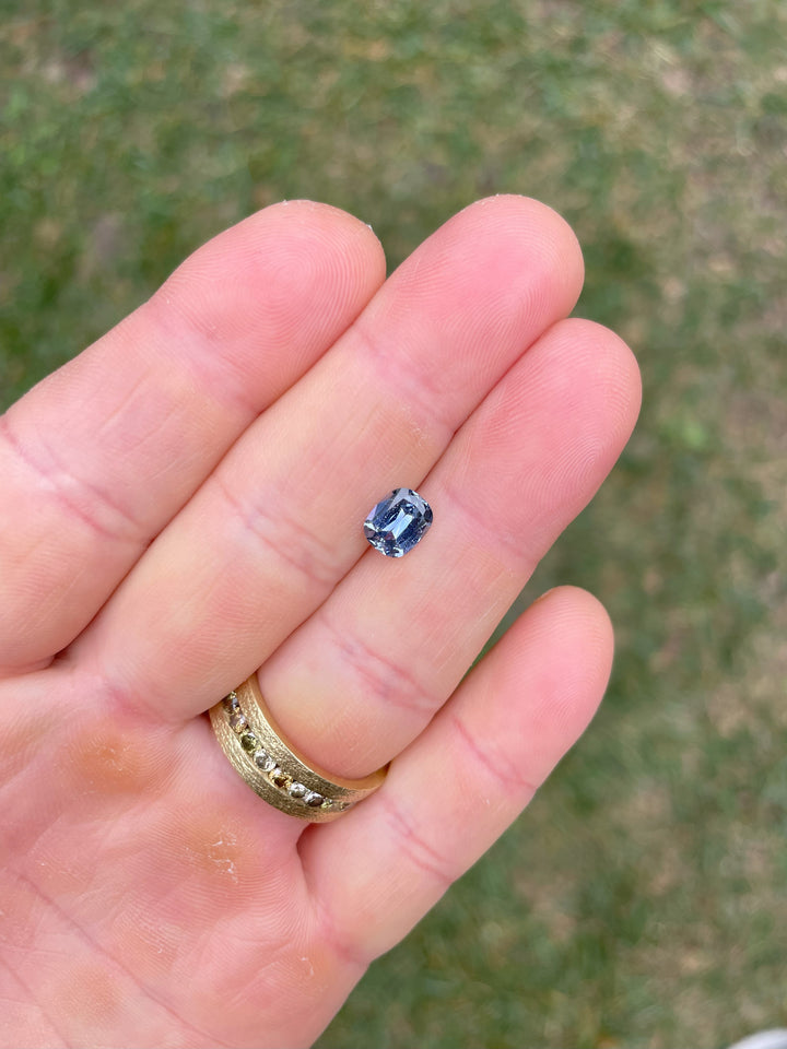 Top view of a 1.48-carat Sri Lankan sapphire in denim blue and cornflower hues, cushion modified cut, reflecting natural light.