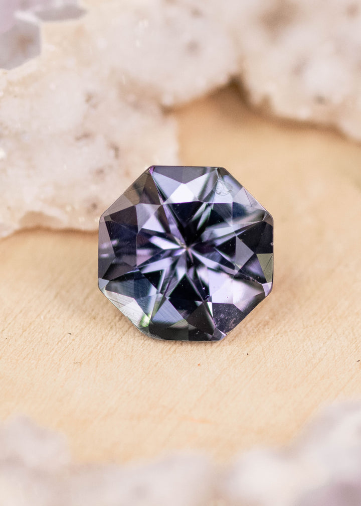 1.49 carat teal green lavender purple Tanzanite custom brilliant octagon placed on display surface, Tanzania origin gemstone highlighting precision faceting, vivid color variation and brilliance for bespoke jewelry
