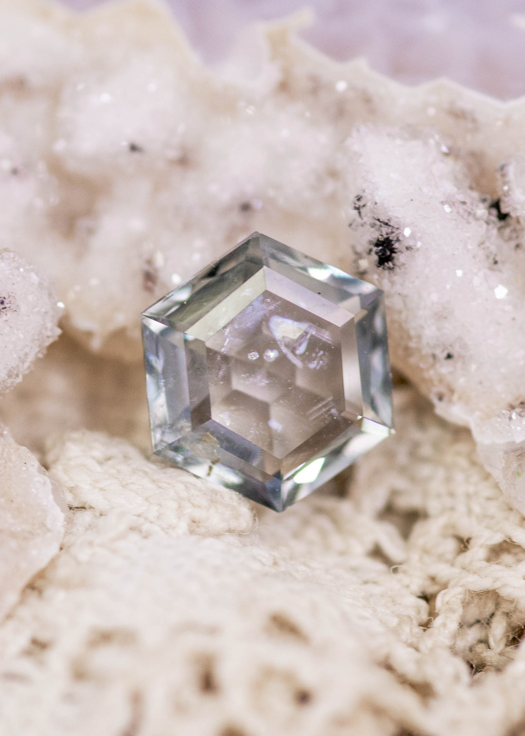 1.49 carat unheated Montana sapphire in green violet teal tones shown on natural crystal background, hexagon step cut gemstone from El Dorado Bar Deposit displaying color shift and geometric faceting.