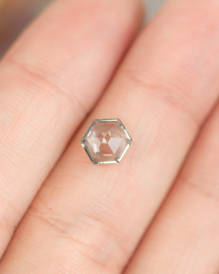 1.49 carat green violet teal Montana sapphire resting on fingers for scale, hexagon step cut gemstone with natural color shift and precision faceting from El Dorado Bar Deposit, USA.