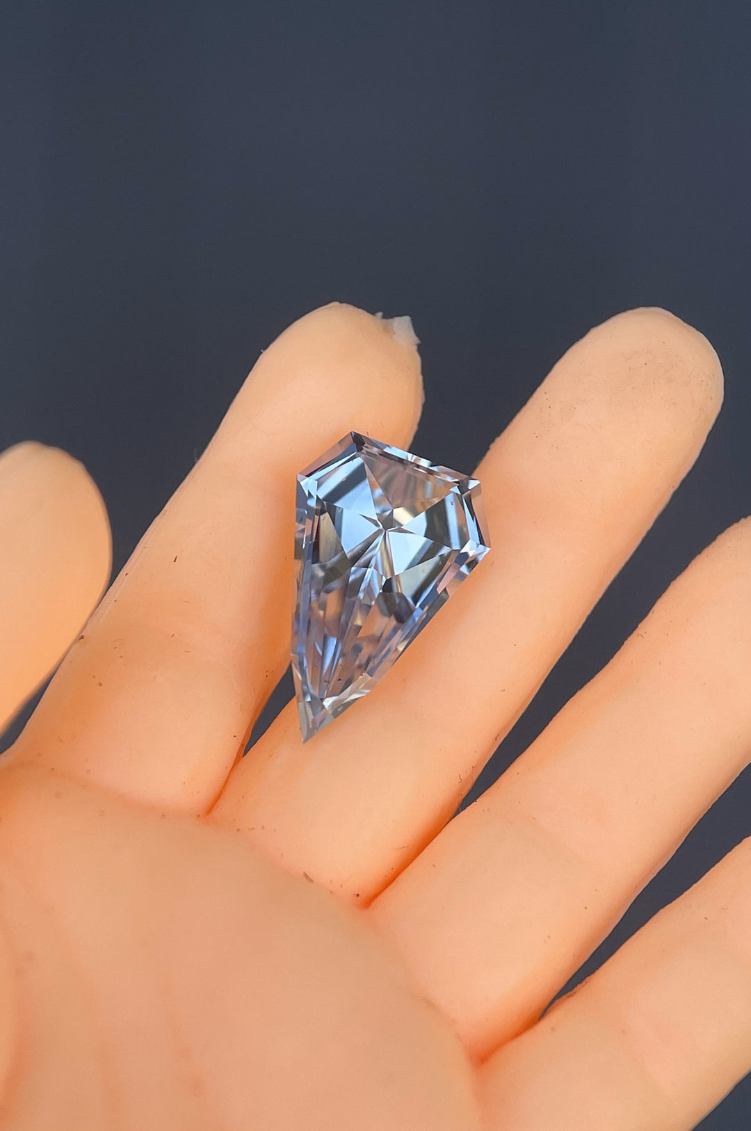 A unique 1.50-carat shield-shaped sapphire featuring a step cut and a blend of gray, blue, and yellow hues. Ethically sourced from Sri Lanka, this gemstone is untreated and exhibits exceptional clarity and brilliance.