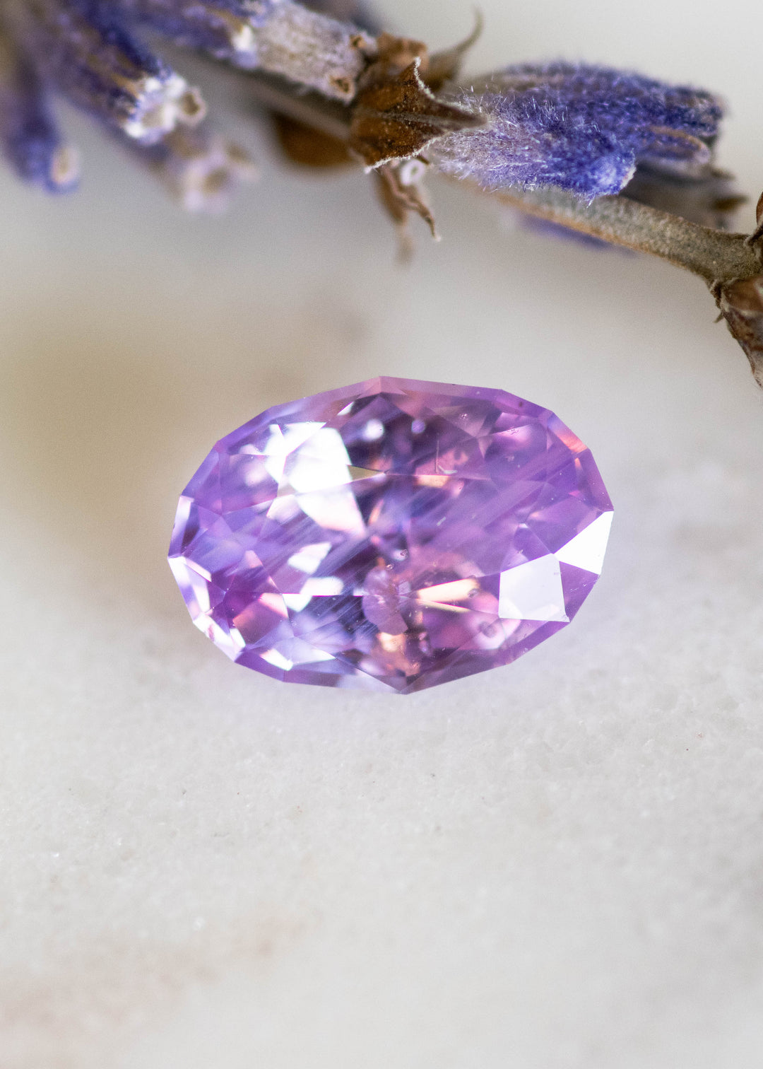1.50ct opalescent violet pink sapphire oval mix cut from Ratnapura Sri Lanka shown on white background