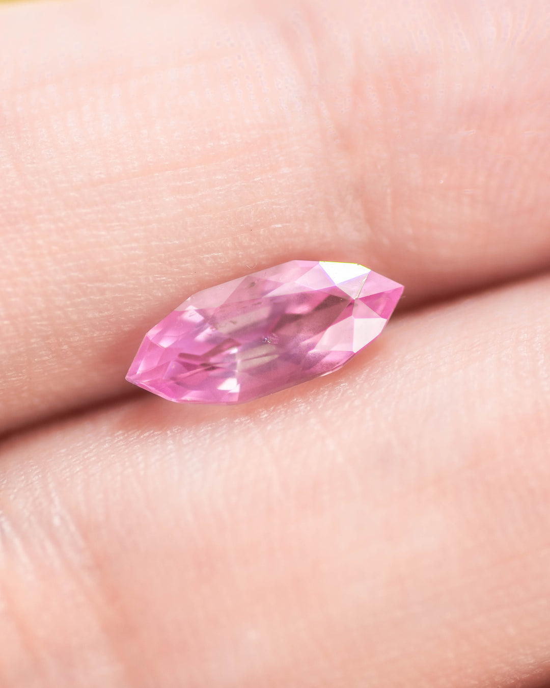 1.50 carat bubblegum pink sapphire displayed on fingertips, revealing radiant sparkle and clarity through the precision marquise mixed cut, untreated sapphire from Sakaraha, Madagascar.